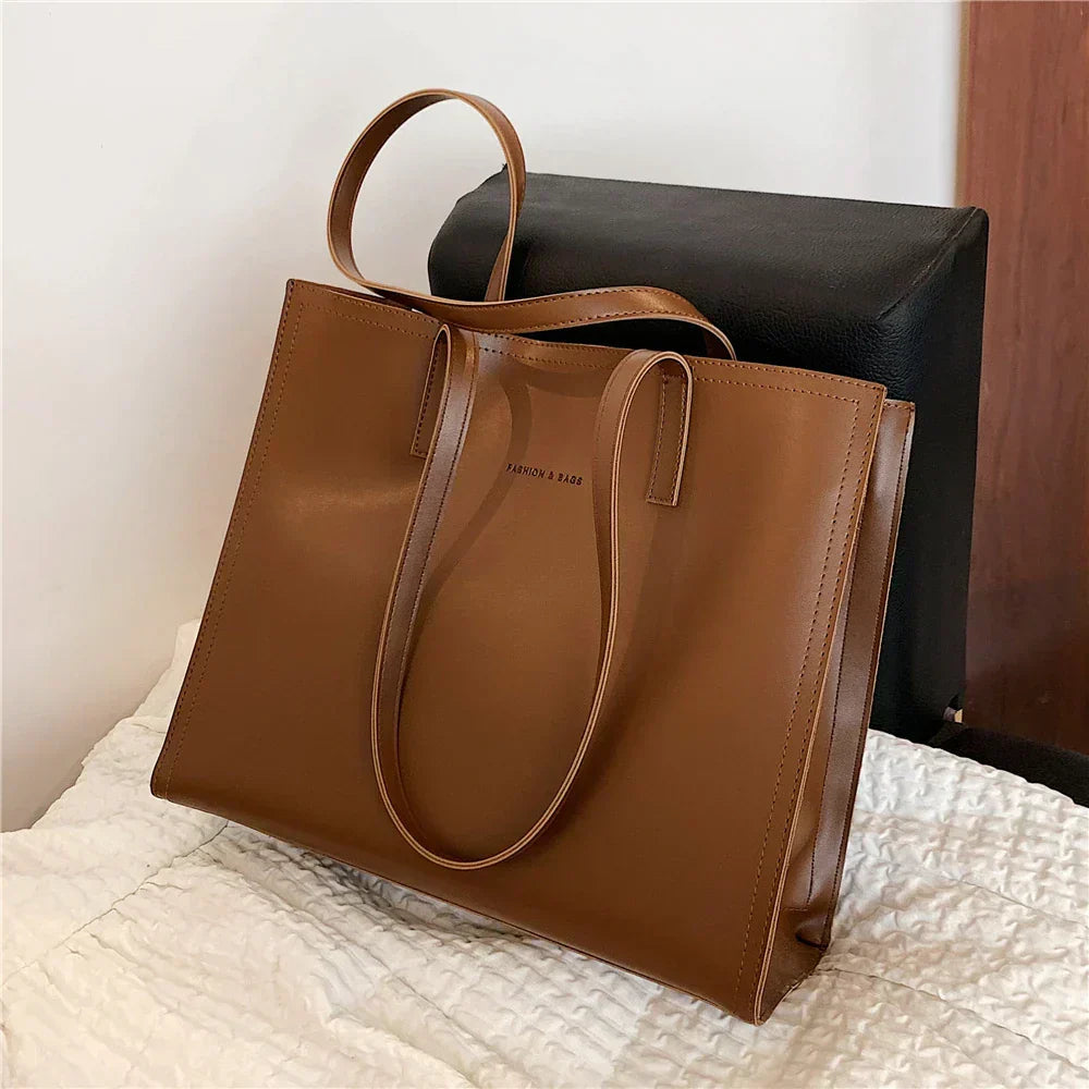 Sac à main en cuir marron élégant sur une chaise noire, design minimaliste, parfait pour la mode féminine, accessoire tendance et chic.