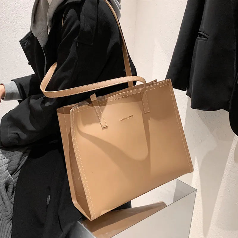 Sac à main beige élégant en cuir, porté par une personne en manteau noir. Accessoire mode tendance, idéal pour un look chic et moderne.