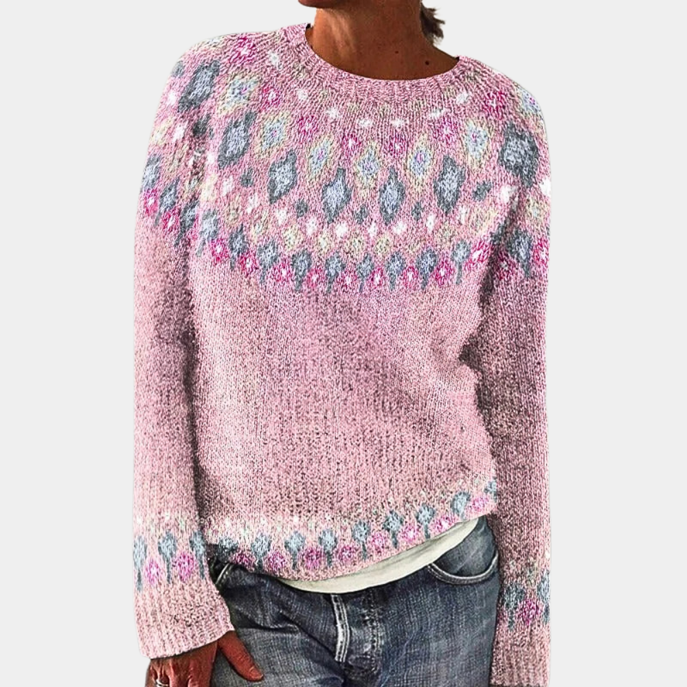 Pull en laine rose avec motifs géométriques colorés, manches longues, col rond, porté par une personne, style décontracté, mode automne-hiver.