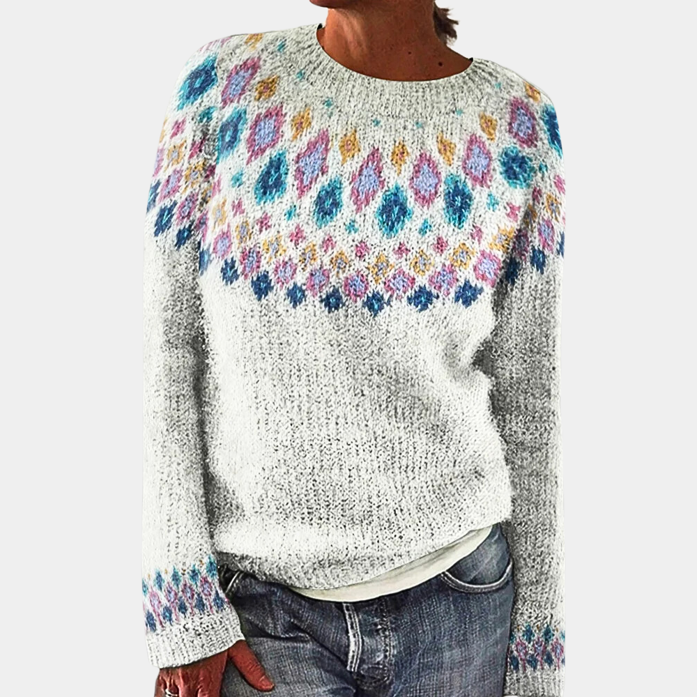 Pull-over en laine gris avec motif coloré géométrique sur le buste et les manches, porté par une personne en jean. Mode hiver, style décontracté.