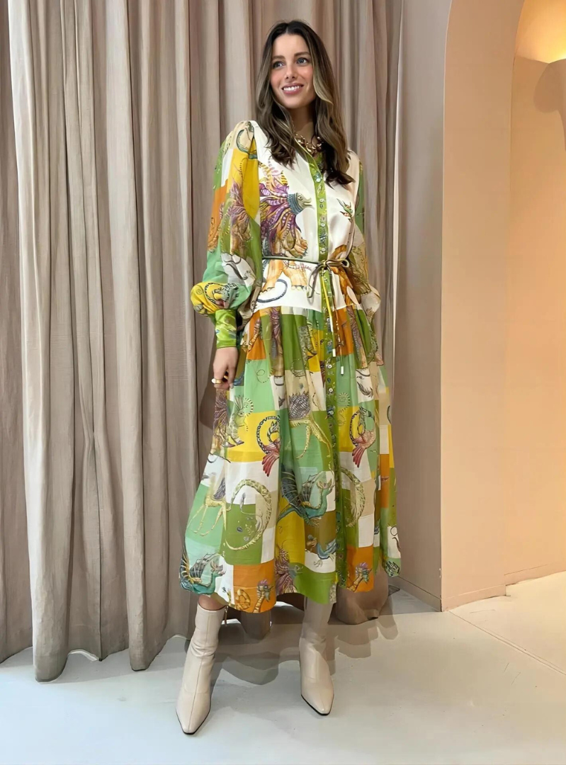 Robe longue colorée à motifs géométriques, ceinturée à la taille, portée par une femme souriante. Mode élégante, tendance automne, style chic.