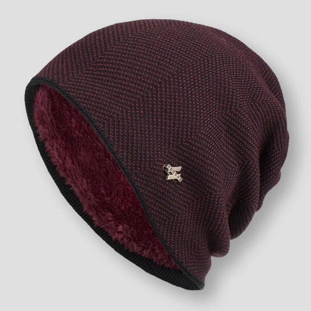 Bonnet en laine bordeaux avec doublure en fourrure, motif chevrons, et broche métallique. Accessoire hiver élégant et chaud.