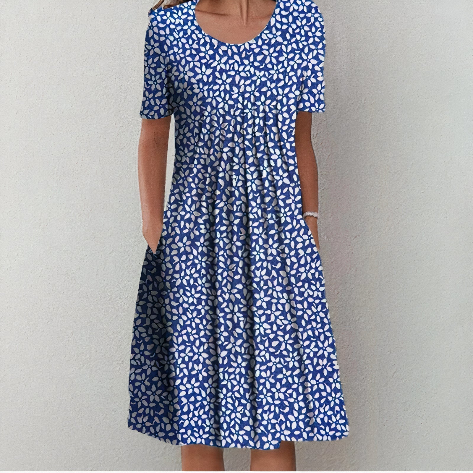 Robe d'été bleue à motifs floraux blancs, manches courtes, coupe évasée, poches latérales, idéale pour un look décontracté et élégant.
