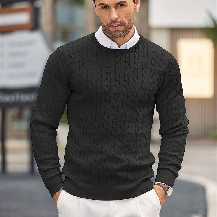 Homme portant un pull noir torsadé élégant, chemise blanche en dessous, debout à l'extérieur. Mode masculine automne-hiver, style décontracté chic.