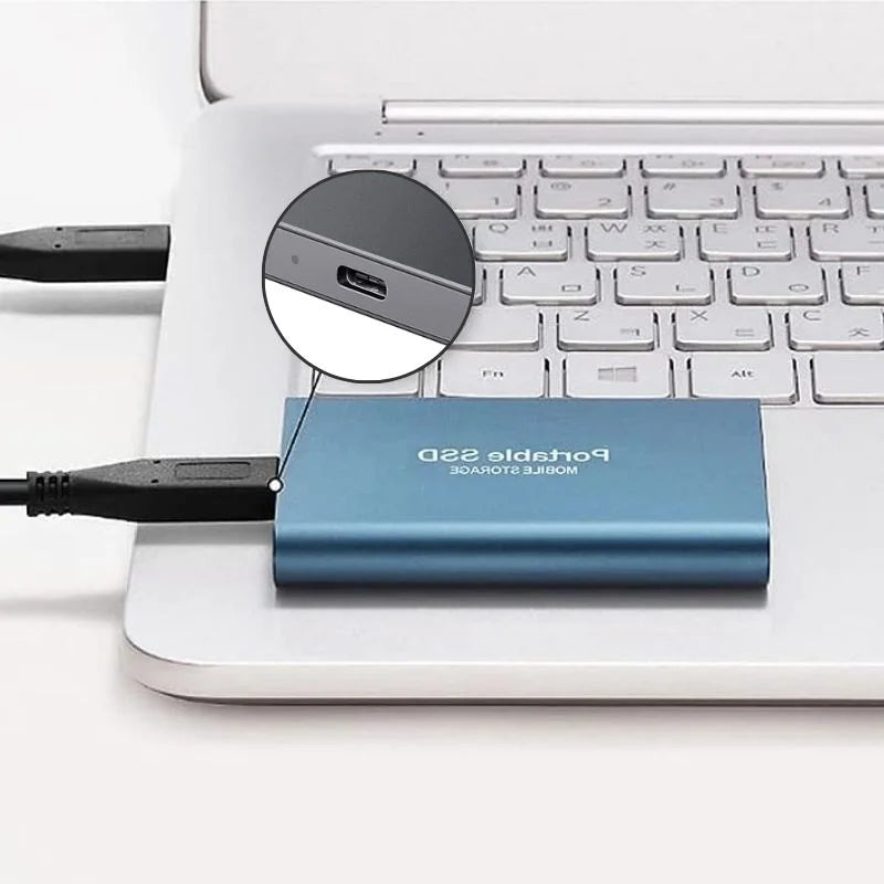 Disque SSD portable bleu connecté à un ordinateur portable argenté via un câble USB, illustrant le stockage externe rapide et compact.
