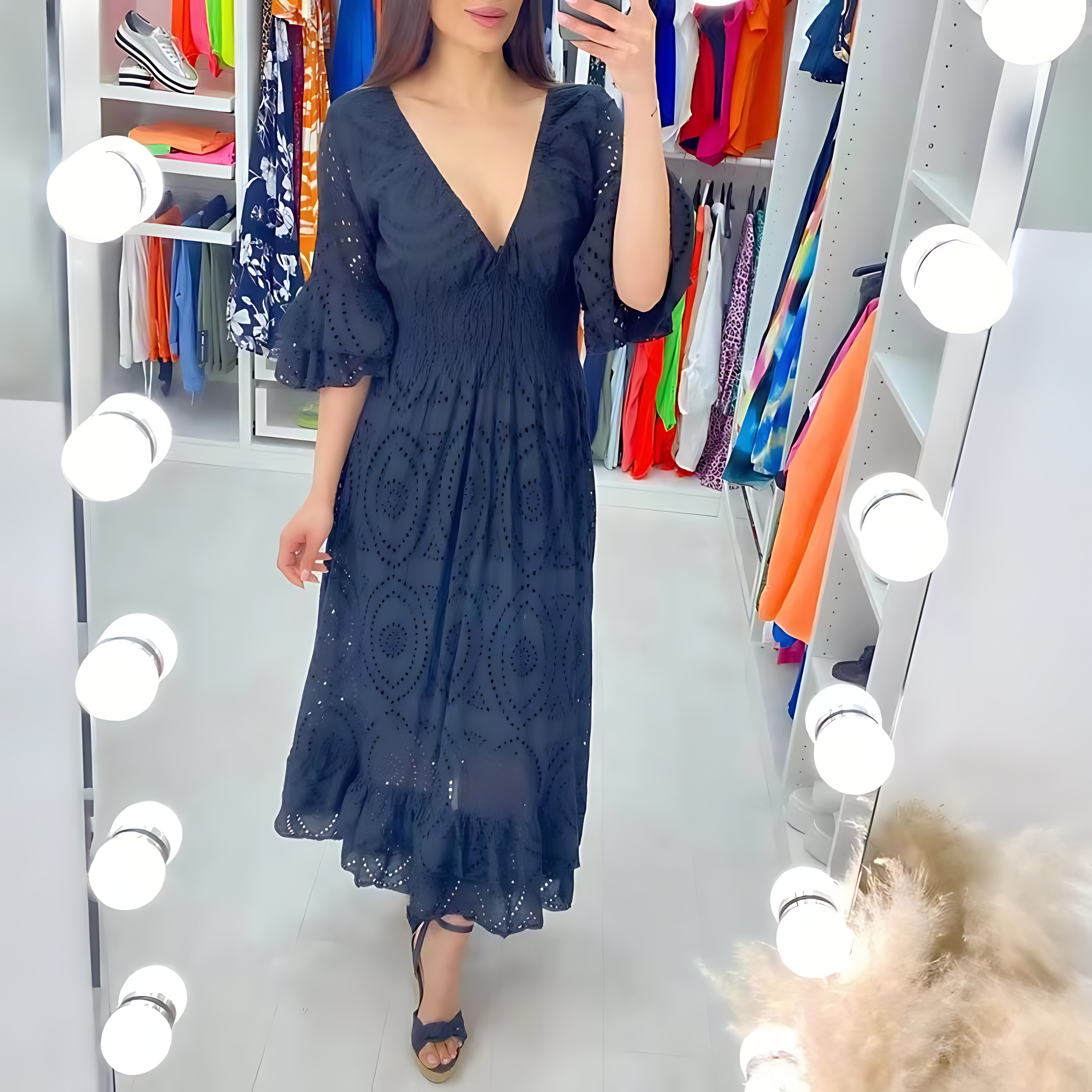 Femme en robe noire élégante à motifs, se tenant devant un miroir éclairé dans un dressing coloré. Mode, style, tenue chic, robe longue.