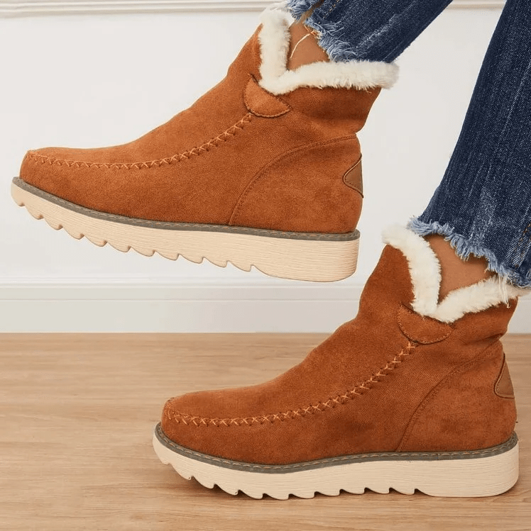 Bottes en daim marron avec doublure en fourrure blanche, semelles crantées, portées avec un jean déchiré. Chaussures d'hiver tendance et confortables.