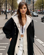 Jeune femme élégante en manteau noir et blanc, marchant sur une rue urbaine animée, mode automne, style moderne, ville, journée.