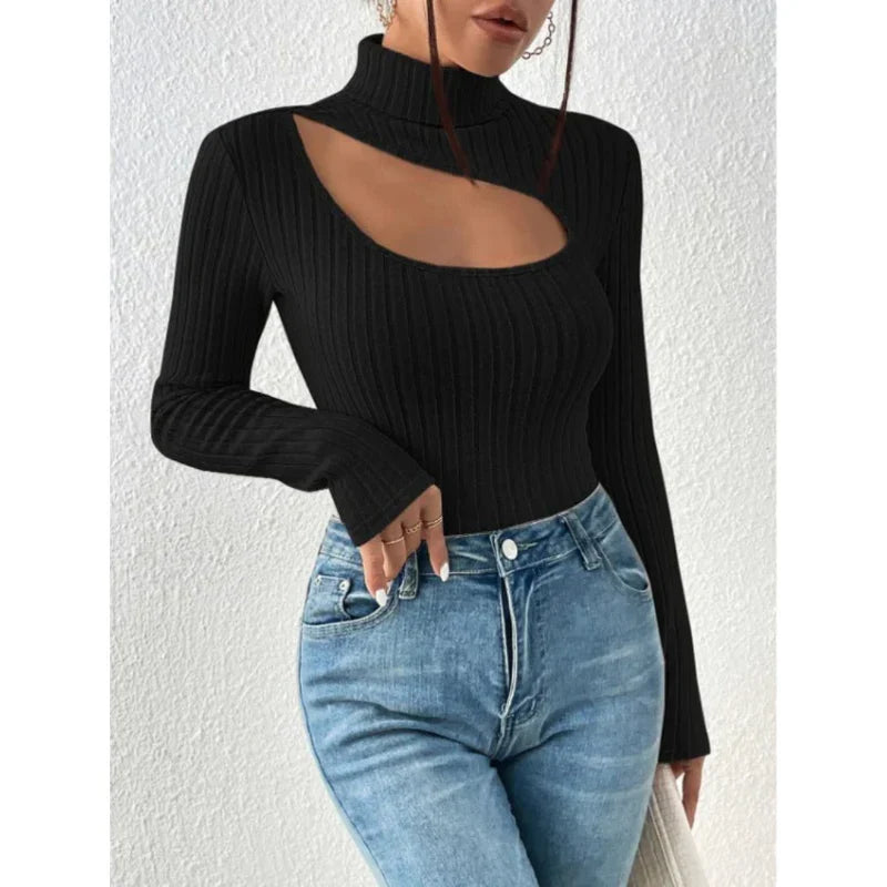 Femme portant un pull noir à col roulé avec découpe asymétrique, associé à un jean bleu. Mode tendance, style chic et moderne.