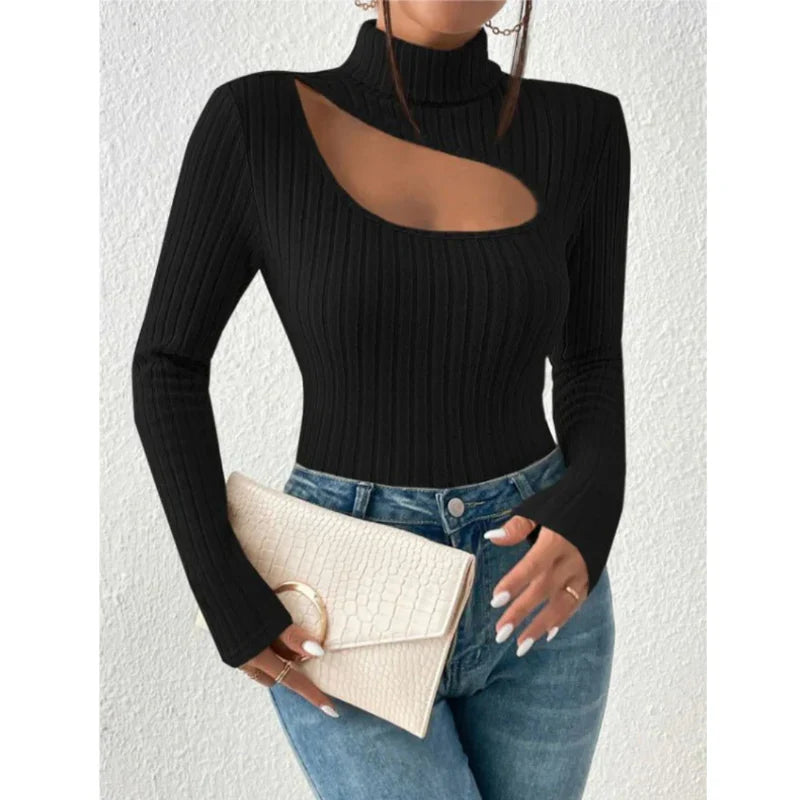 Femme portant un pull noir à découpe asymétrique, tenant une pochette beige texturée, avec un jean bleu. Mode élégante et moderne.