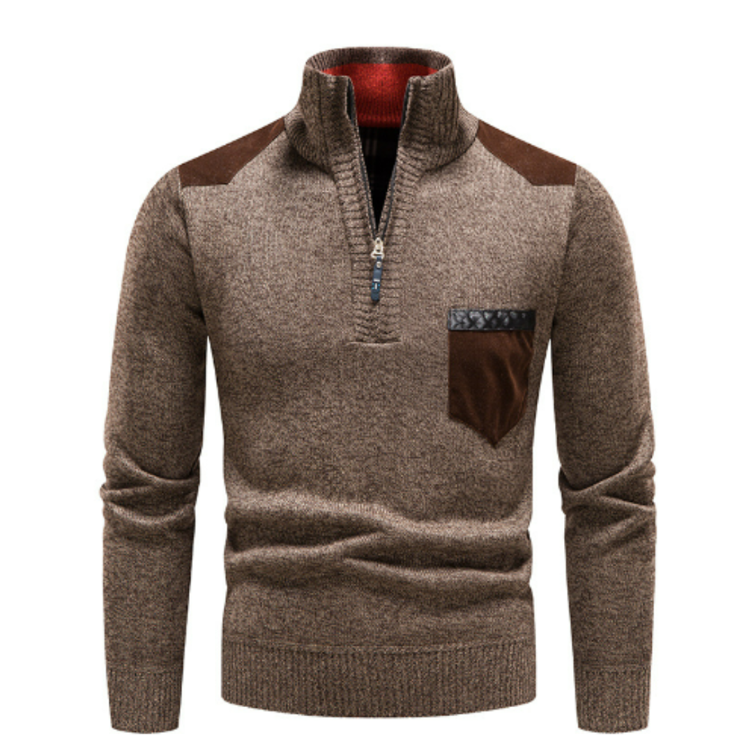 Pull-over marron en laine avec col zippé, poche poitrine en cuir marron et empiècements aux épaules. Mode homme automne-hiver élégant.