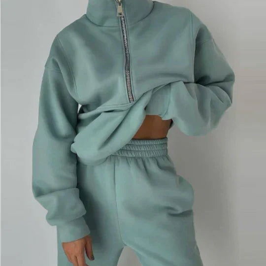 Personne portant un ensemble de survêtement vert menthe, avec un sweat à fermeture éclair et un pantalon assorti. Mode décontractée, tendance streetwear.