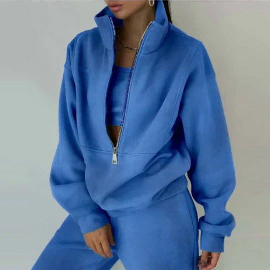 Femme portant un ensemble de survêtement bleu avec fermeture éclair, style décontracté, mode tendance, vêtements confortables pour l'automne.
