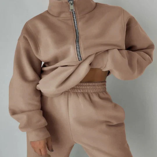 Sweat beige à col zippé, manches longues, porté avec un pantalon assorti. Tenue décontractée et tendance pour l'automne. Mode féminine confortable.