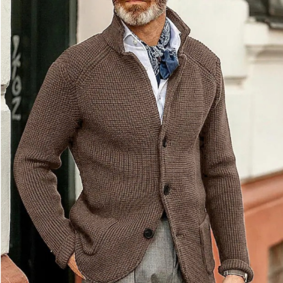 Homme élégant portant un cardigan marron texturé, chemise blanche et foulard bleu, style automne chic, mode masculine moderne, look urbain sophistiqué.