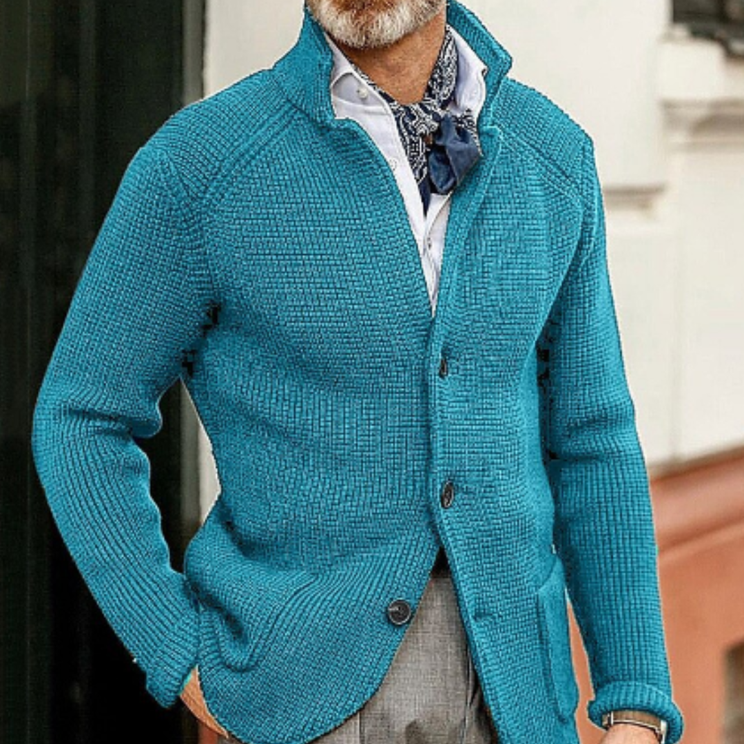 Homme portant un cardigan bleu en tricot, chemise blanche et foulard bleu, style élégant et moderne, mode masculine automne-hiver.