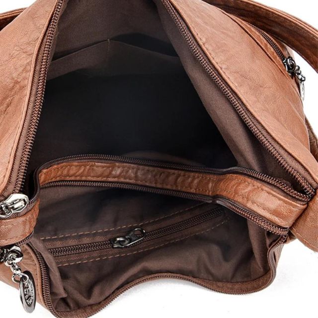 Sac à main en cuir marron ouvert, montrant plusieurs compartiments zippés. Accessoire de mode élégant et pratique pour femme.