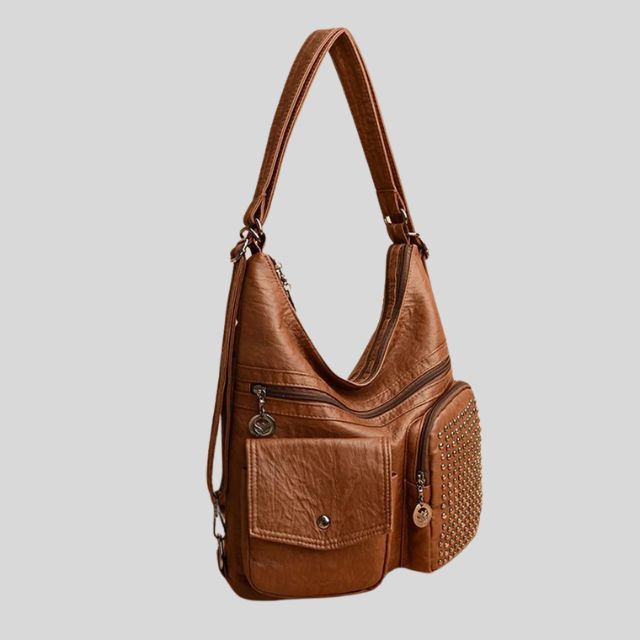 Sac à main en cuir marron avec bandoulière, poches zippées et détails cloutés. Accessoire mode élégant et pratique pour femme.