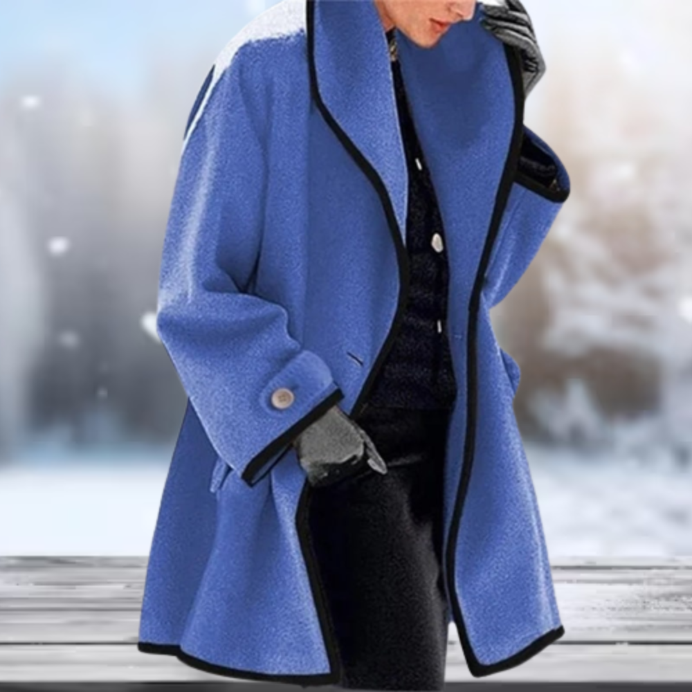 Manteau bleu élégant avec bordure noire, porté par une personne en hiver. Mode hiver, vêtement chaud, style chic. Fond flou enneigé.