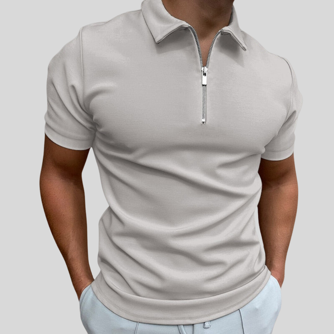 Homme portant un polo gris clair à fermeture éclair, manches courtes, style décontracté. Mode masculine, tendance, élégance moderne.
