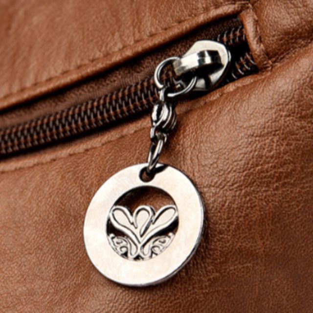 Gros plan sur une fermeture éclair en cuir marron avec un pendentif en métal argenté, motif cœur. Accessoire de mode élégant et tendance.