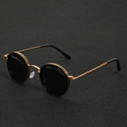Lunettes de soleil rondes vintage avec monture dorée et verres noirs, posées sur fond noir. Accessoire mode élégant et tendance.