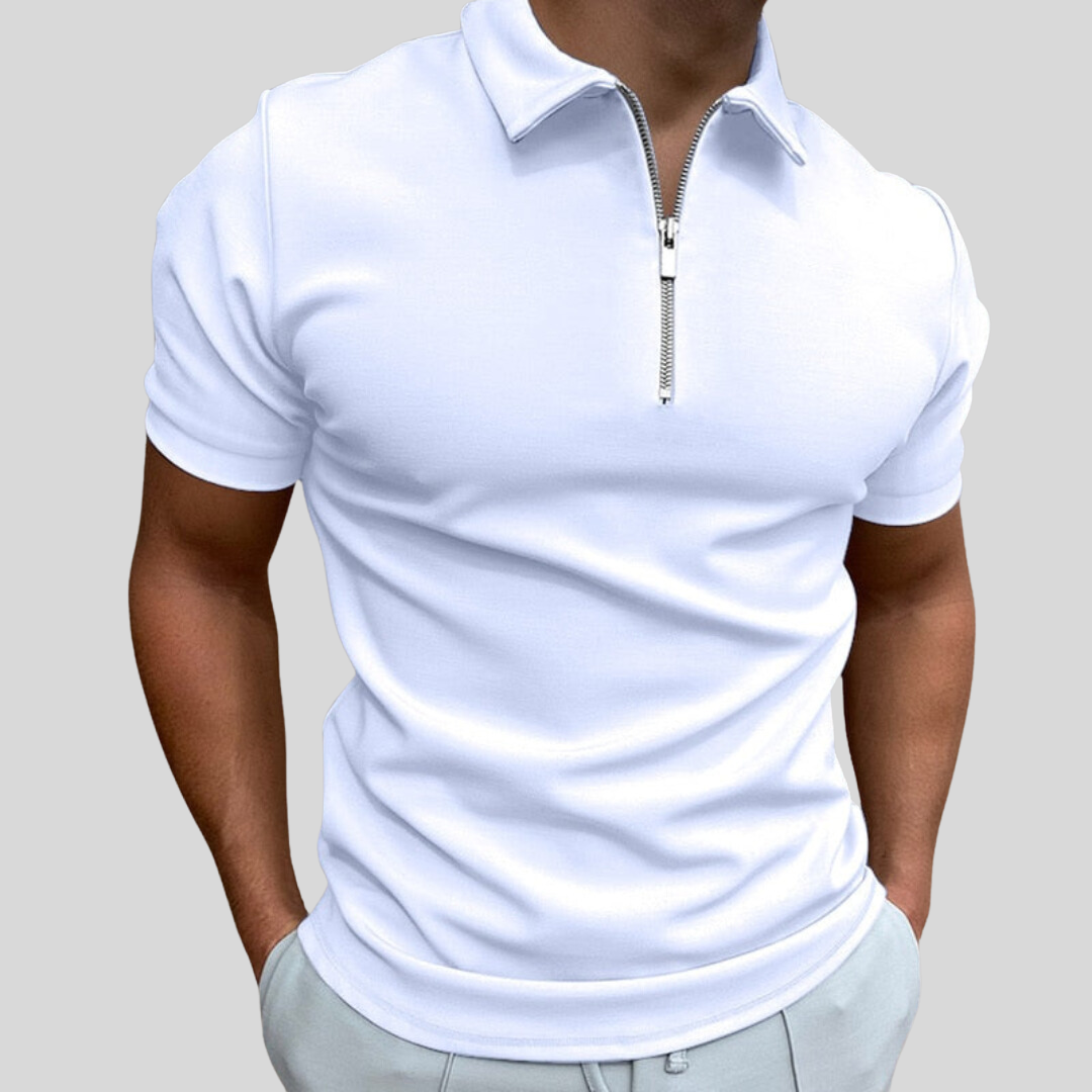 Homme portant un polo blanc à fermeture éclair, manches courtes, sur fond gris. Mode masculine élégante, tenue décontractée chic.
