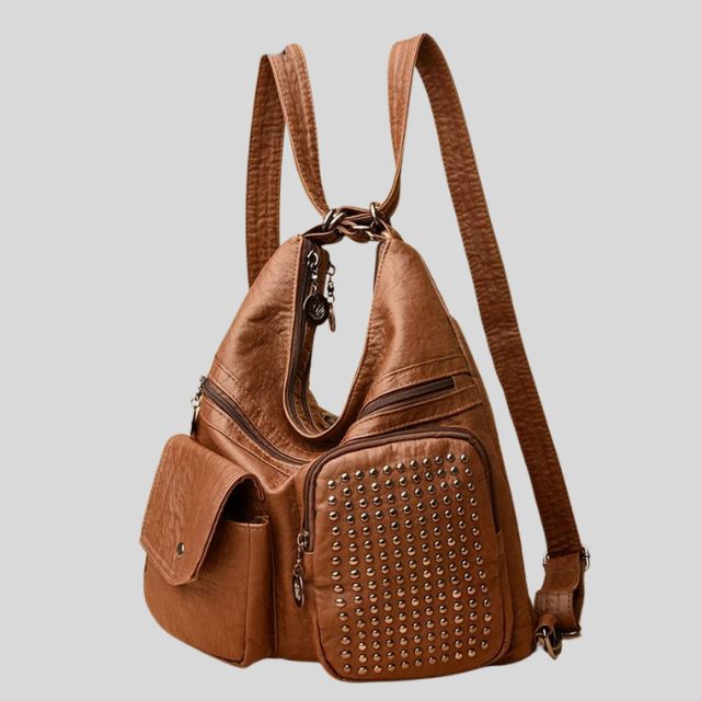 Sac à dos en cuir marron avec clous décoratifs, poches zippées et rabat. Design moderne et fonctionnel pour mode et accessoires tendance.