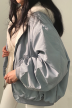 Femme portant une veste bomber bleu clair avec doublure en fourrure blanche, tenue d'hiver élégante, mode féminine tendance, style décontracté.
