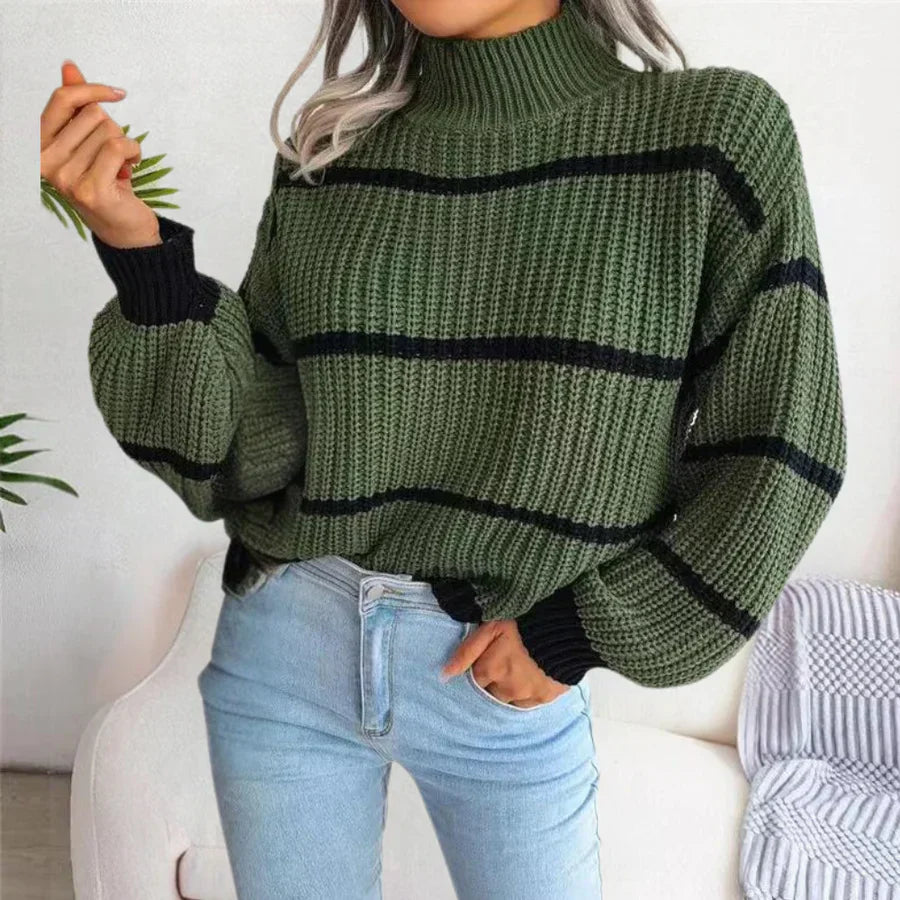 Femme portant un pull vert à col roulé et rayures noires, manches longues, associé à un jean bleu clair. Mode automne-hiver tendance.