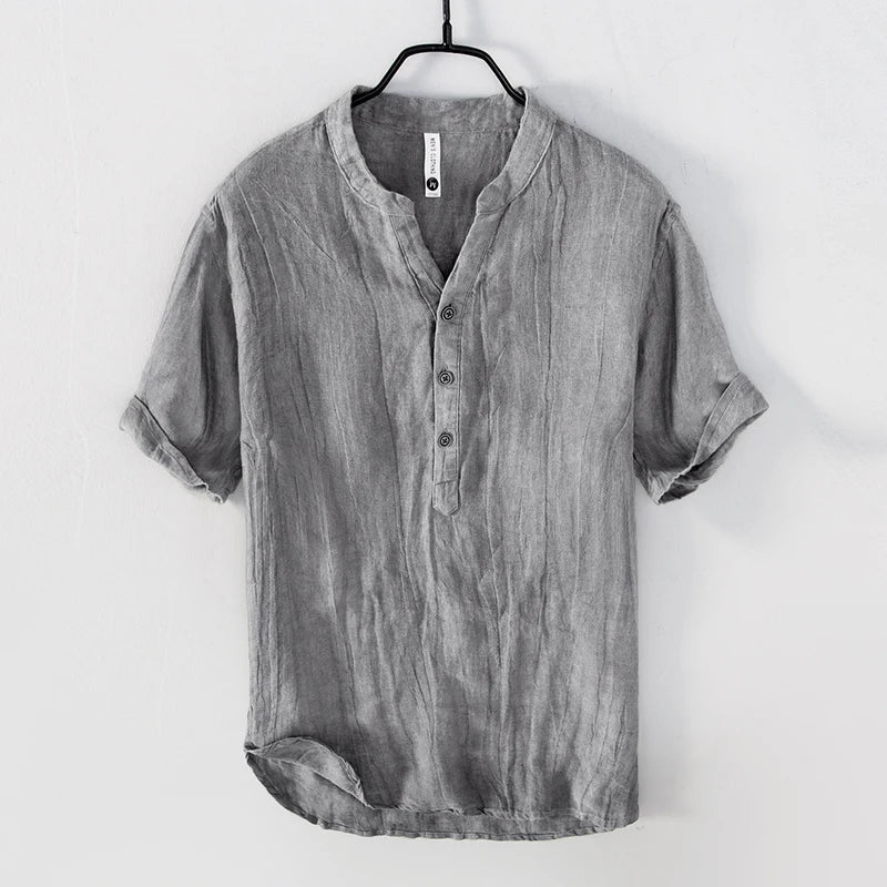 Chemise en lin gris pour homme, manches courtes, col mao, boutons, style décontracté, suspendue sur cintre noir, mode estivale élégante.