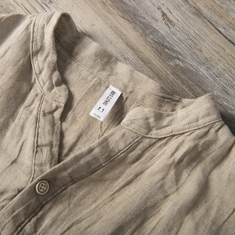 Chemise en lin beige pour homme, col mao, étiquette taille L, posée sur plancher en bois. Mode masculine, vêtement décontracté, style naturel.