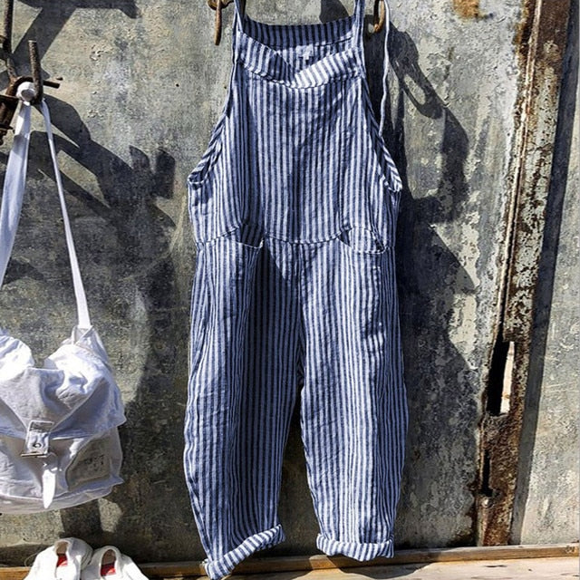 Salopette rayée bleue et blanche suspendue sur un fond industriel en métal, mode décontractée, tendance vintage, style urbain.