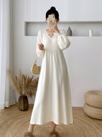 Femme en robe longue blanche élégante, prenant un selfie dans un intérieur moderne avec décoration minimaliste et plantes pampas.