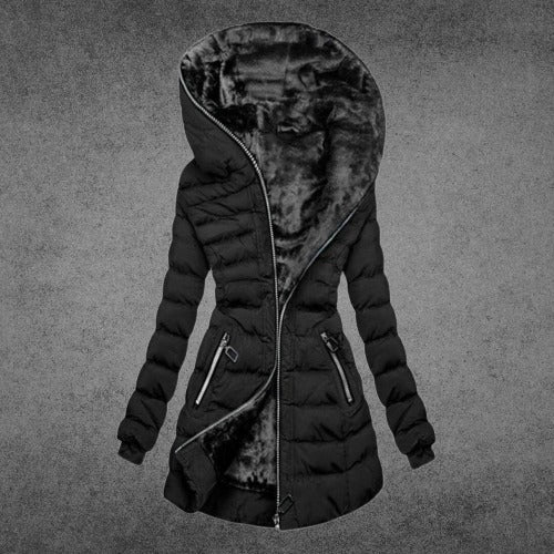 Manteau noir matelassé pour femme avec capuche en fausse fourrure, fermeture asymétrique, poches zippées, style hiver élégant et moderne.