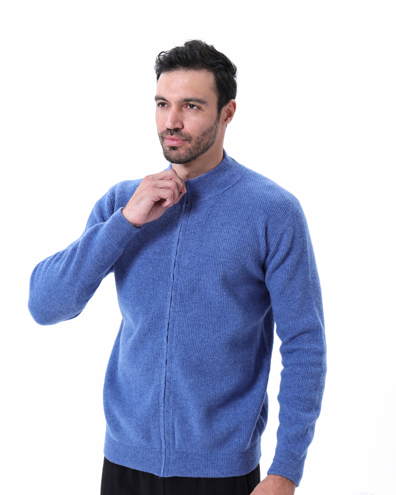 Homme portant un pull bleu en laine, col montant, manches longues, sur fond blanc. Mode masculine, vêtement hiver, style décontracté.