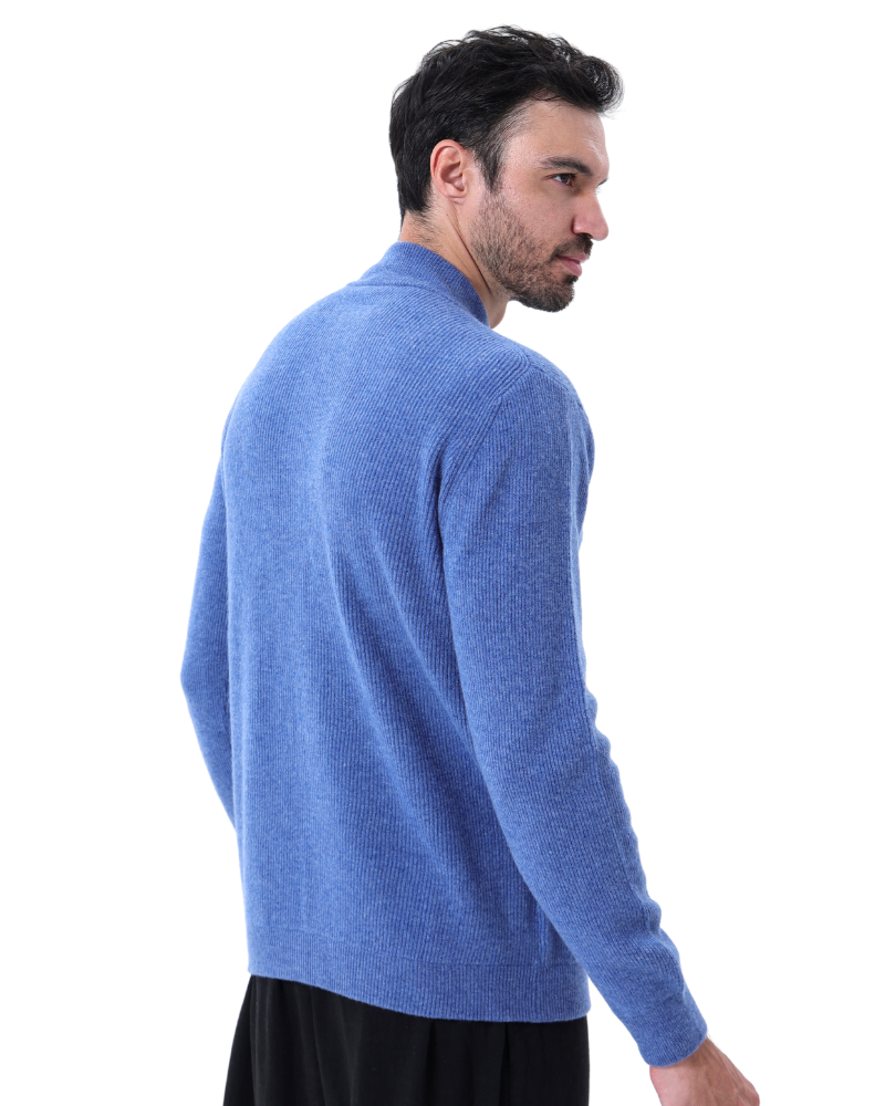 Homme portant un pull bleu en laine, manches longues, col montant, sur fond blanc. Mode masculine, vêtement hiver, style décontracté.