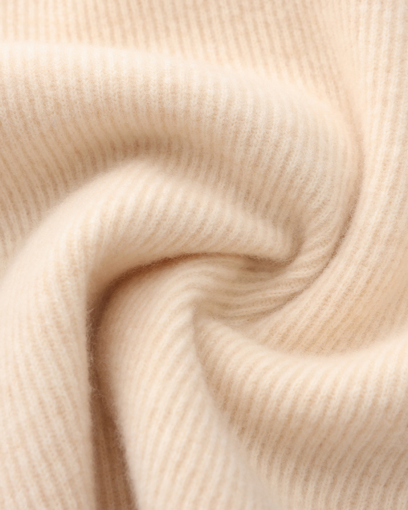 Texture douce de tissu en cachemire beige, gros plan. Motif côtelé, textile luxueux et chaud, idéal pour vêtements d'hiver élégants.