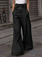 Pantalon large noir femme, taille haute avec ceinture, mode urbaine chic, rue pavée, style élégant et moderne, tendance automne-hiver.