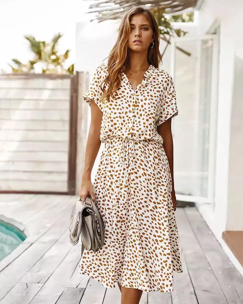 Femme portant une robe à motifs léopard, debout près d'une piscine. Mode estivale, tenue décontractée, style chic et tendance.