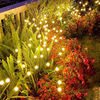Jardin illuminé avec des guirlandes lumineuses LED solaires, plantes vertes et feuillage coloré, ambiance nocturne chaleureuse et décorative.