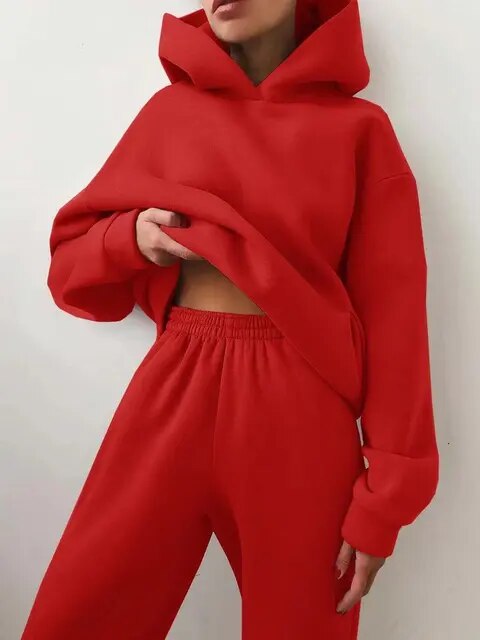 Personne portant un ensemble de survêtement rouge vif avec capuche, style décontracté et moderne, mode tendance automne-hiver, confort et élégance.