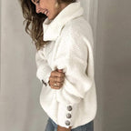 Femme souriante portant un pull blanc à col roulé, manches longues avec boutons décoratifs, style décontracté et élégant, mode automne-hiver.