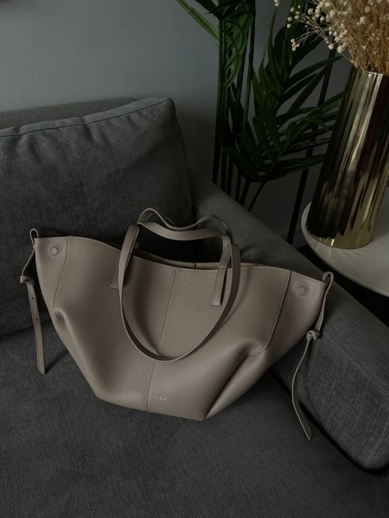 Sac à main en cuir beige sur un canapé gris, design moderne et élégant, idéal pour la mode féminine. Accessoire tendance et chic.