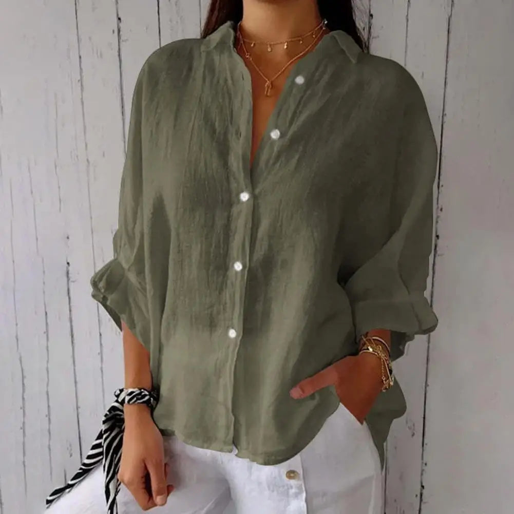 Chemise en lin vert olive pour femme, manches longues, boutons blancs, style décontracté, associée à un pantalon blanc, fond bois clair.