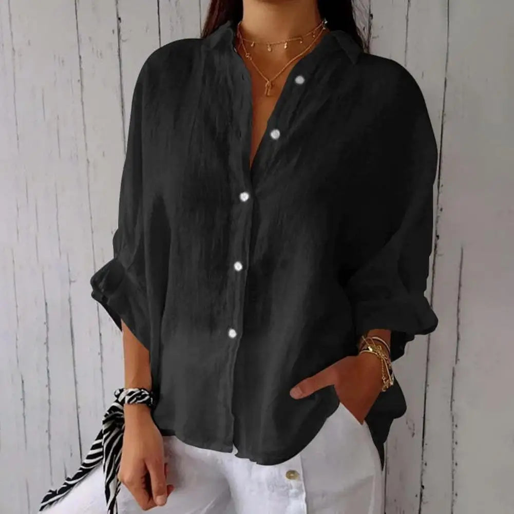 Chemise noire ample en lin pour femme, manches longues retroussées, boutons blancs, associée à un pantalon blanc. Style décontracté et élégant.