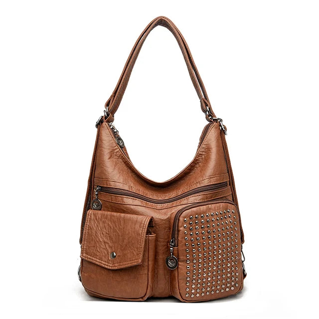 Sac à main en cuir marron avec clous décoratifs, poches zippées et bandoulière. Accessoire mode femme élégant et pratique.