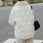 Veste matelassée blanche avec col en fourrure, portée par une personne dans la rue. Mode hiver, style élégant, tendance urbaine.