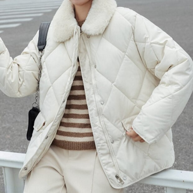 Veste matelassée blanche avec col en fourrure, portée par une personne en pull rayé et pantalon beige, mode hiver élégante et confortable.