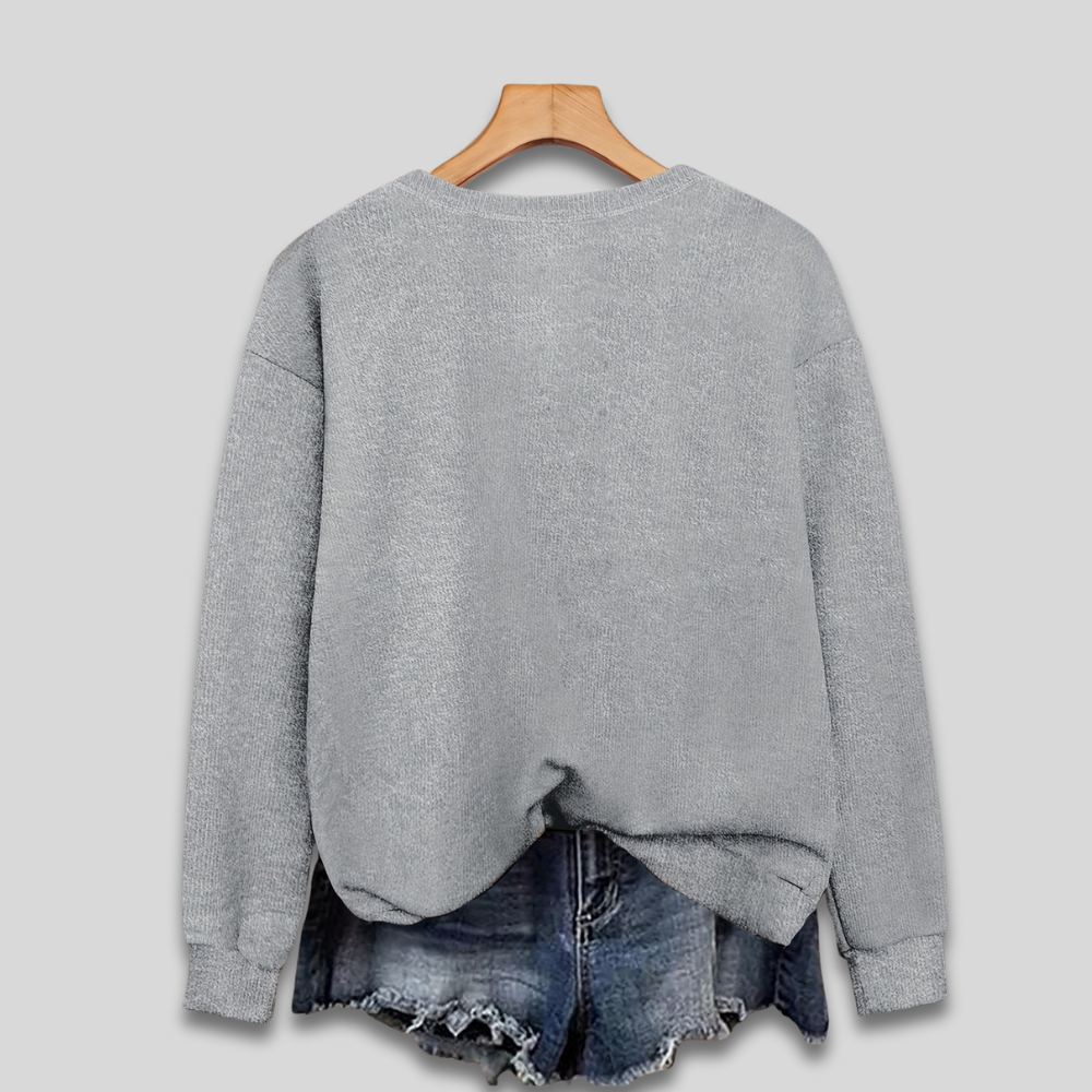 Pull gris en laine sur cintre en bois, associé à un short en jean délavé. Mode décontractée, vêtements d'automne, style tendance.